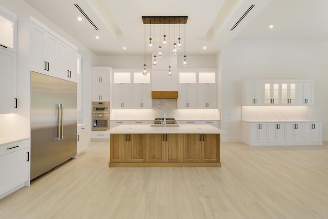 kitchen with stainless steel appliances, white cabinetry, pendant lighting, and a large island with sink