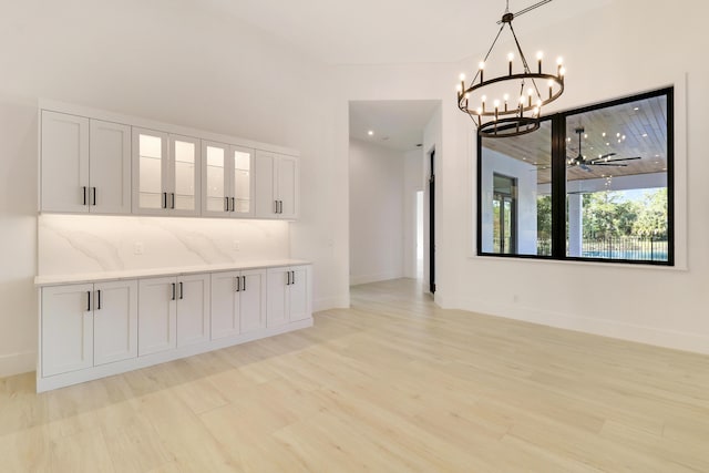 interior space with light hardwood / wood-style floors and ceiling fan with notable chandelier