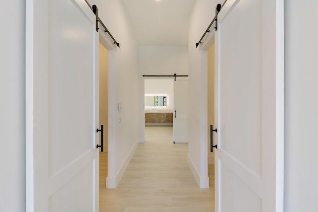 hall with light hardwood / wood-style floors and a barn door