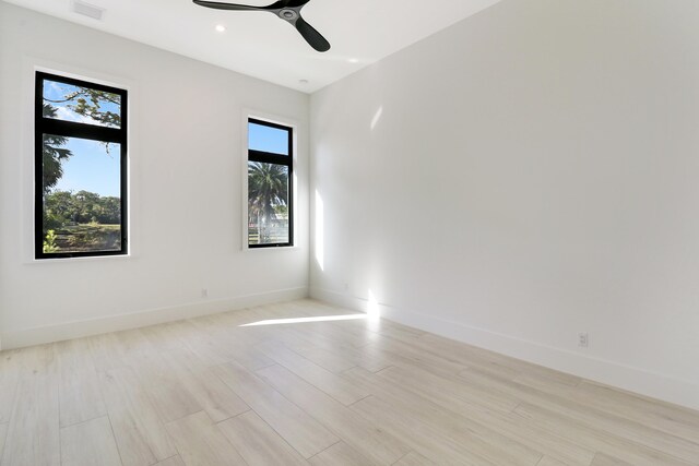 spare room with ceiling fan, a wealth of natural light, and light hardwood / wood-style flooring