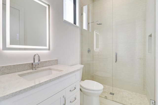 bathroom featuring toilet, vanity, and a shower with door