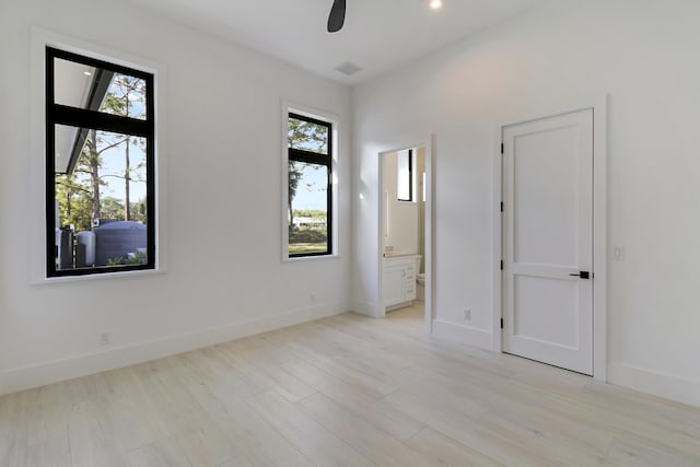 empty room featuring ceiling fan, a wealth of natural light, and light wood-type flooring