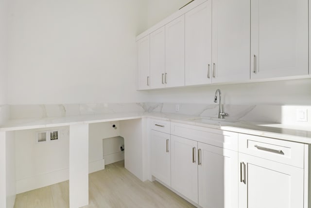 clothes washing area featuring cabinets, electric dryer hookup, sink, hookup for a washing machine, and light wood-type flooring