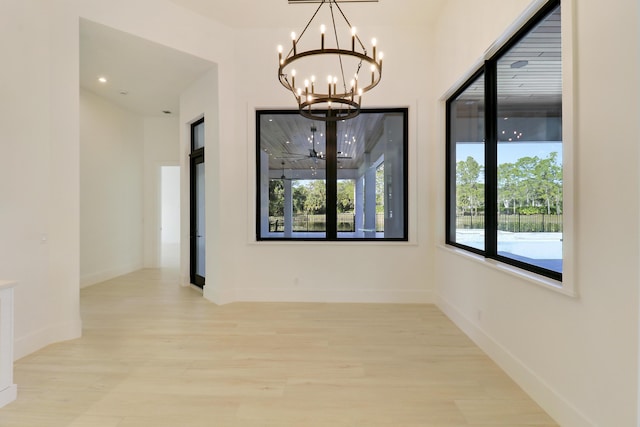 interior space featuring light wood-type flooring, plenty of natural light, and an inviting chandelier