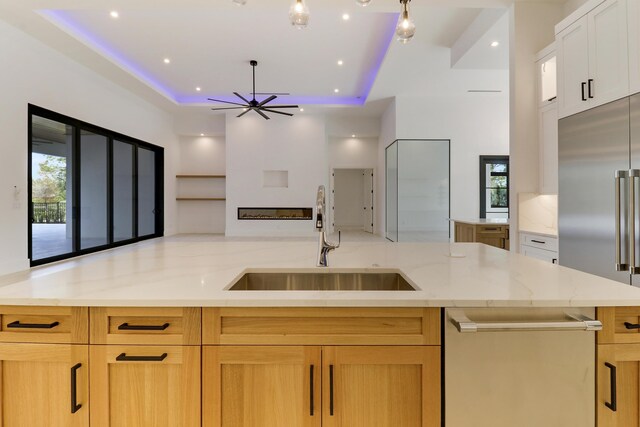 kitchen featuring ceiling fan, white cabinetry, light stone counters, and sink