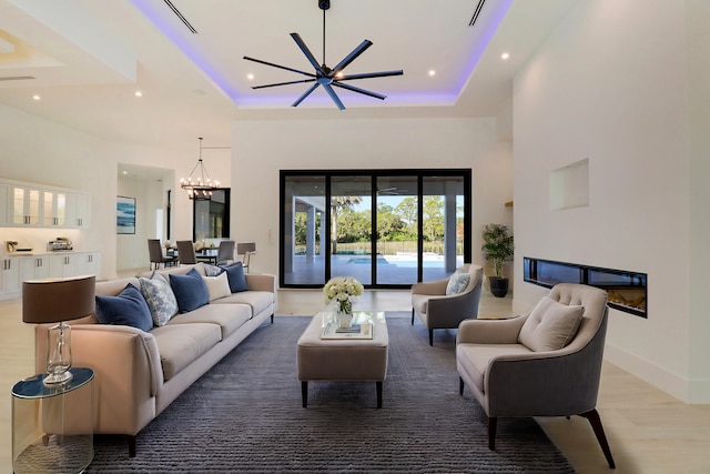 living room featuring a tray ceiling, a high ceiling, hardwood / wood-style floors, and a notable chandelier