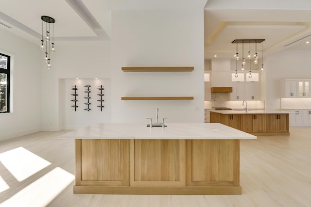 kitchen with hanging light fixtures, white cabinets, and a large island with sink