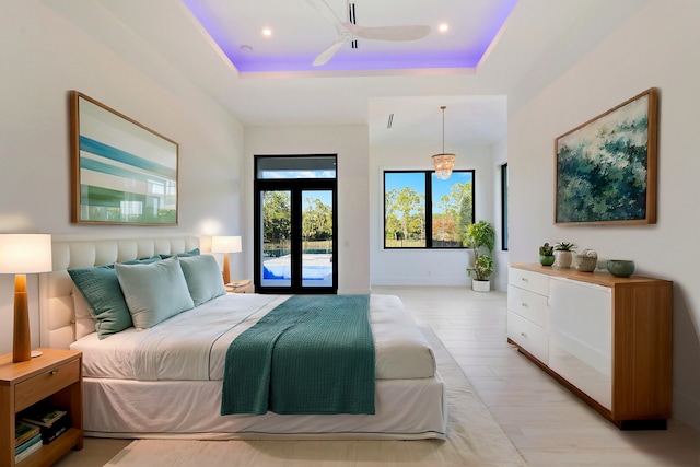 bedroom featuring french doors, light hardwood / wood-style flooring, access to outside, a tray ceiling, and ceiling fan