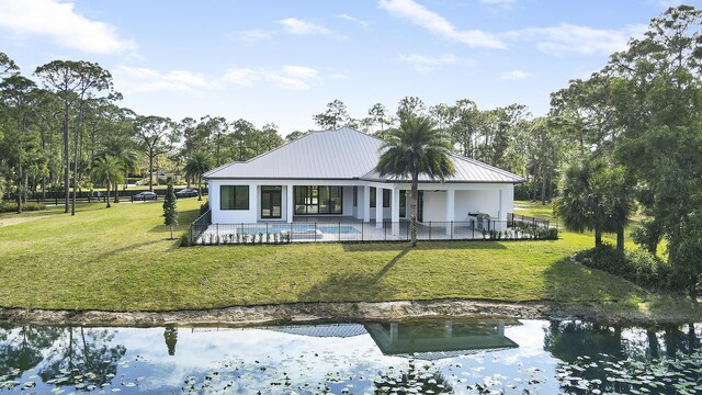 back of house with a water view, a patio area, and a yard