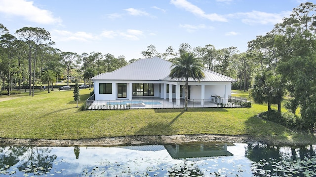 rear view of property featuring a water view, a patio, and a lawn