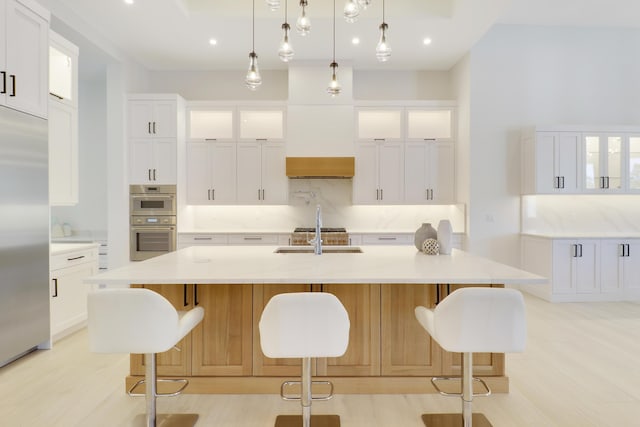 kitchen with a spacious island, white cabinetry, stainless steel appliances, and sink