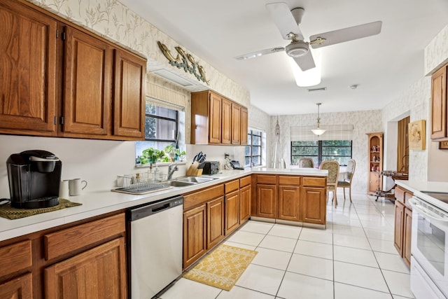 kitchen featuring a peninsula, wallpapered walls, brown cabinetry, and stainless steel dishwasher