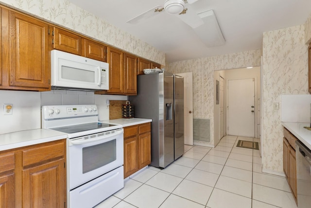 kitchen with stainless steel appliances, brown cabinets, light countertops, and wallpapered walls