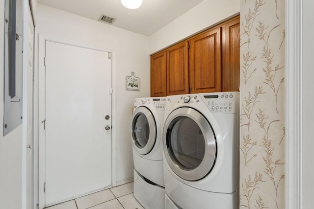 laundry room with visible vents, separate washer and dryer, light tile patterned flooring, and cabinet space