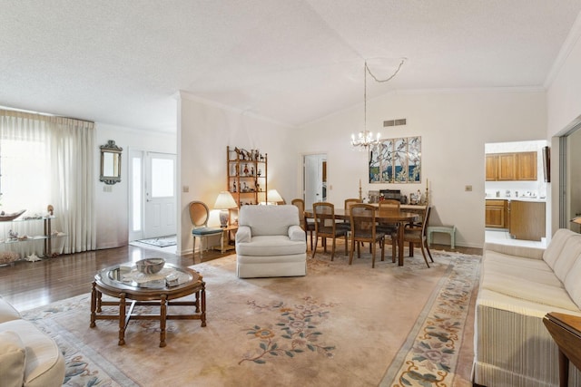 living area with visible vents, lofted ceiling, crown molding, light wood-type flooring, and a chandelier