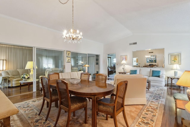 dining space with visible vents, light wood-style flooring, an inviting chandelier, crown molding, and high vaulted ceiling