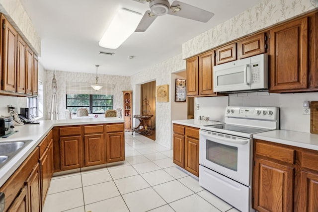 kitchen featuring white appliances, visible vents, light countertops, brown cabinetry, and wallpapered walls