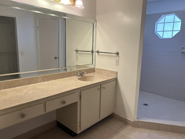 bathroom with tile patterned flooring, vanity, and tiled shower