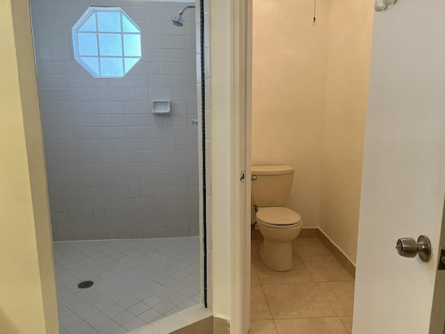 bathroom with tile patterned flooring, a tile shower, and toilet