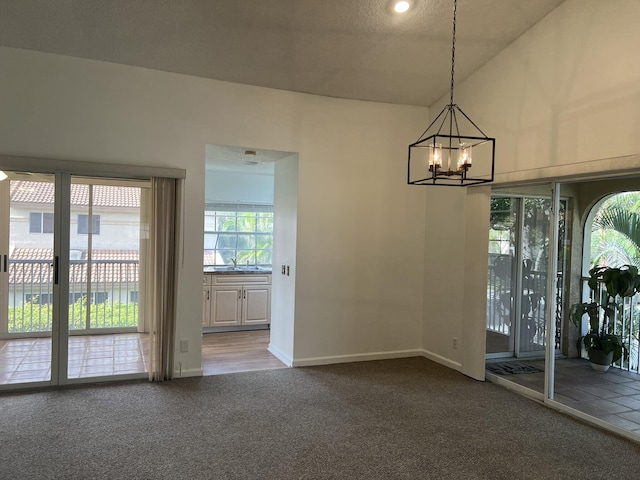 empty room with carpet, a chandelier, and lofted ceiling