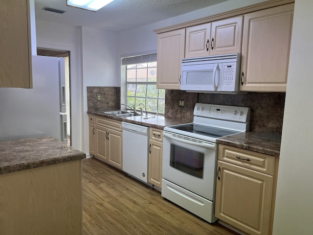 kitchen featuring white appliances, sink, decorative backsplash, a textured ceiling, and light hardwood / wood-style floors