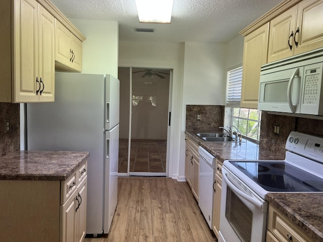 kitchen with light wood-type flooring, a textured ceiling, white appliances, and sink