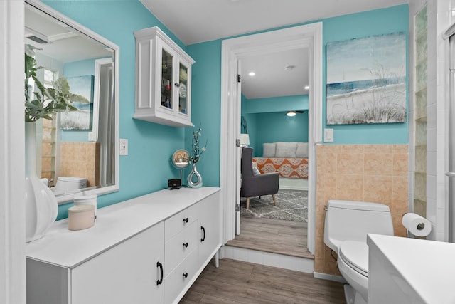 bathroom with hardwood / wood-style flooring, toilet, and tile walls