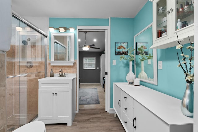 bathroom with ceiling fan, a shower with door, vanity, and hardwood / wood-style flooring