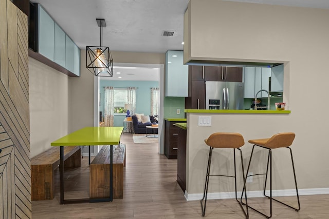 kitchen with stainless steel fridge with ice dispenser, pendant lighting, wood-type flooring, and dark brown cabinets