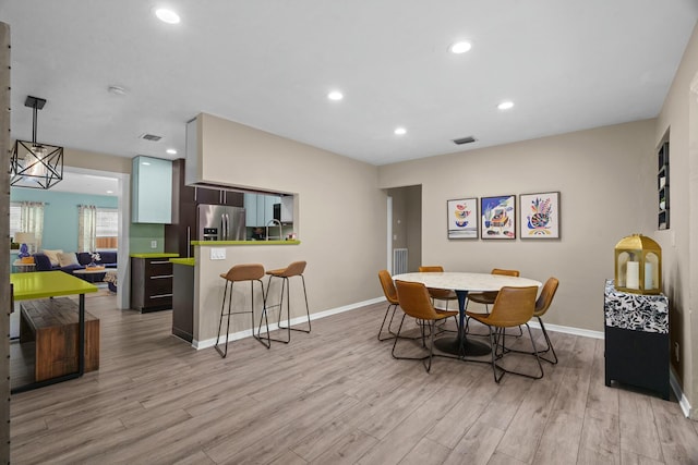 dining space with light wood-type flooring and sink