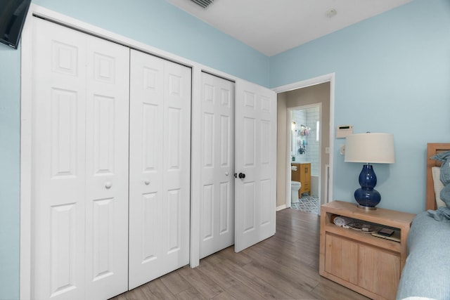 bedroom with light hardwood / wood-style flooring and two closets