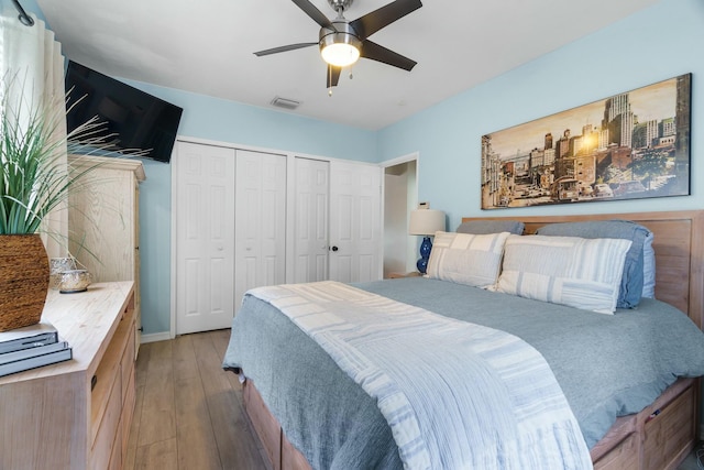 bedroom featuring light hardwood / wood-style floors, ceiling fan, and multiple closets