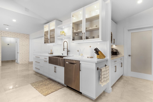 kitchen with lofted ceiling, white cabinets, sink, stainless steel dishwasher, and tasteful backsplash