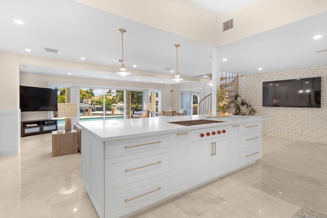 kitchen with white cabinets, pendant lighting, black electric stovetop, and a kitchen island with sink