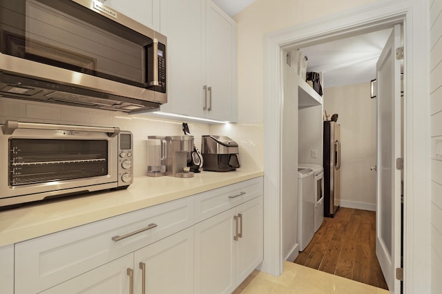 kitchen featuring separate washer and dryer, tasteful backsplash, white cabinetry, wood-type flooring, and stainless steel appliances