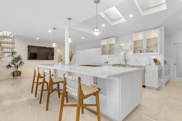 kitchen with sink, pendant lighting, a breakfast bar area, decorative backsplash, and white cabinets