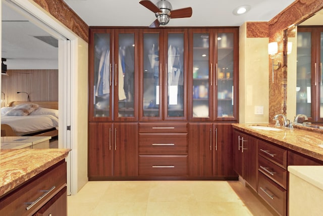 interior space featuring light stone countertops, ceiling fan, and sink