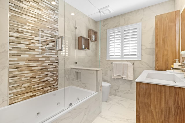 full bathroom featuring tile walls, vanity, tiled shower / bath combo, and toilet