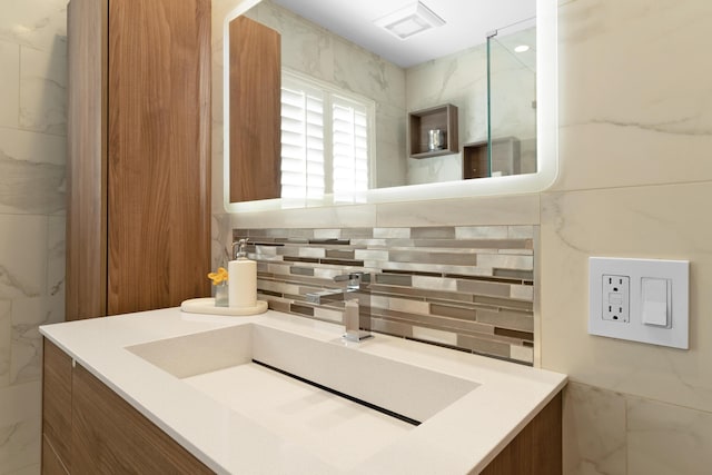 bathroom featuring vanity, decorative backsplash, and tile walls