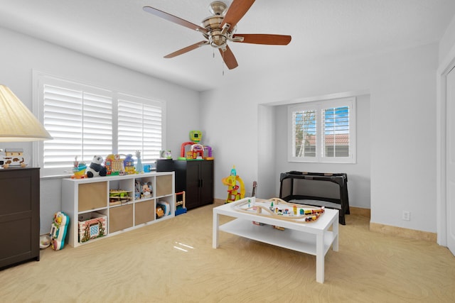 recreation room featuring light carpet and ceiling fan