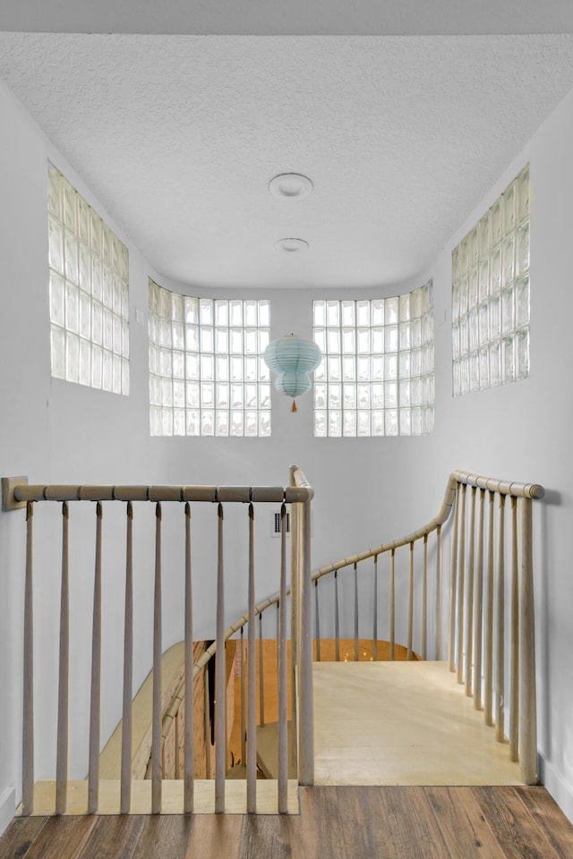 stairs featuring wood-type flooring and a textured ceiling