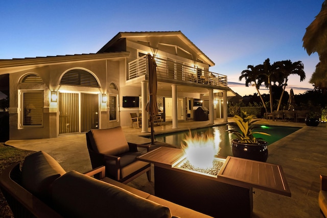 exterior space featuring a balcony and an outdoor living space with a fire pit