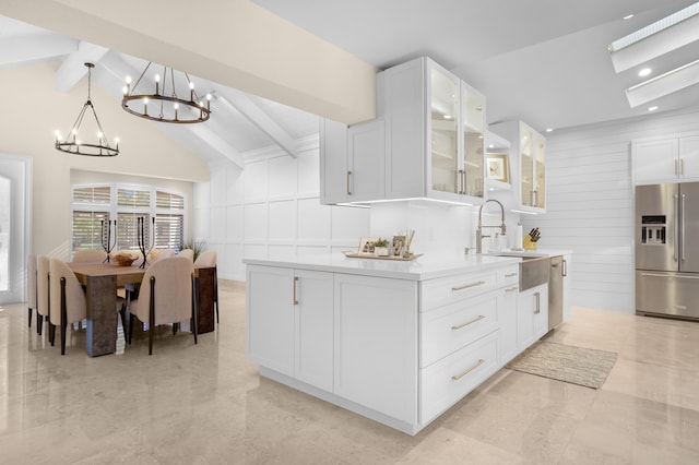 kitchen with stainless steel refrigerator with ice dispenser, sink, lofted ceiling with beams, white cabinets, and hanging light fixtures