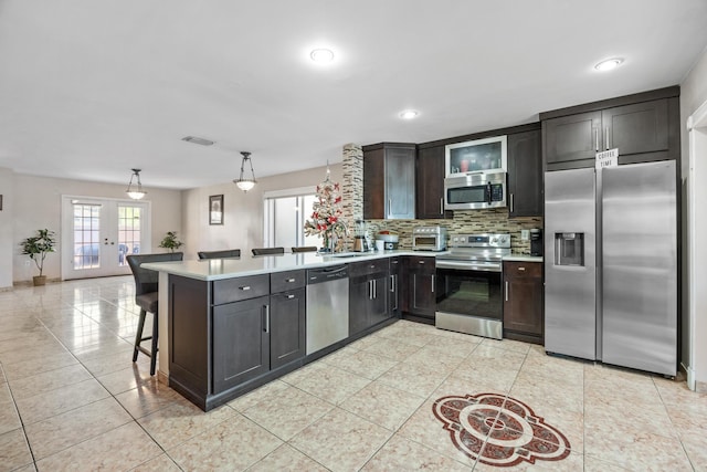 kitchen with sink, french doors, pendant lighting, a breakfast bar, and appliances with stainless steel finishes