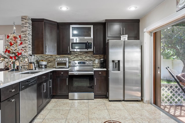 kitchen with dark brown cabinetry, sink, stainless steel appliances, tasteful backsplash, and light tile patterned flooring