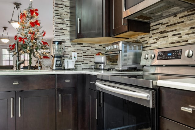 kitchen featuring dark brown cabinetry, decorative backsplash, hanging light fixtures, and stainless steel appliances