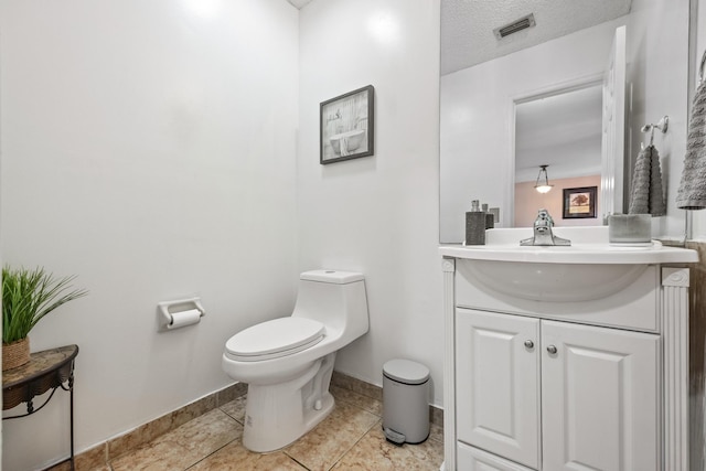 bathroom with tile patterned floors, vanity, a textured ceiling, and toilet