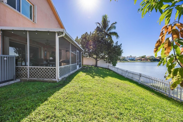 view of yard featuring central air condition unit, a sunroom, and a water view