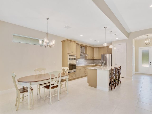 kitchen featuring stainless steel refrigerator with ice dispenser, light brown cabinets, a center island with sink, and a healthy amount of sunlight