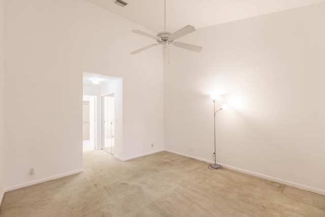 carpeted spare room with ceiling fan and high vaulted ceiling